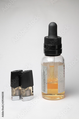 e-juice vape refill pods with with a bottle of orange e-liquid, isolated close up white background photo