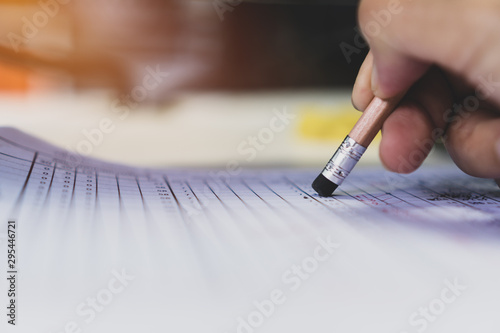 High school student holding pencil eraser for taking exams in examination room, writing answer aptitude test in classroom, view of having quiz competition for entrance to university, Education concept photo