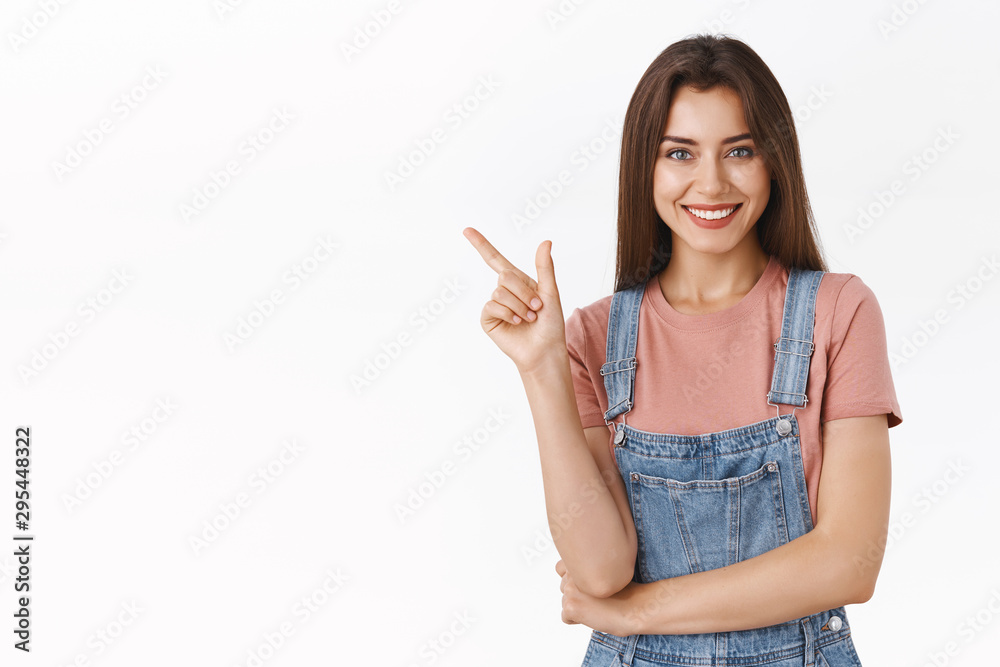 Cheerful, confident stylish modern woman in dungarees, t-shirt pointing upper left corner, laughing and smiling carefree as give hint where buy clothes during black friday, white background Cheerful, confident stylish modern woman in dungarees, t-shirt pointing upper left corner, laughing and smiling carefree as give hint where buy clothes during black friday, white background