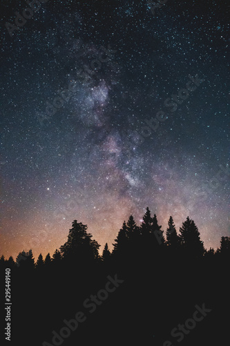 Silhouette of pine trees in the mountains and night sky view with stars and milky way galaxy view at a midnight hiking nature trip. Wurmberg  Braunlage Harz National Park  German Mountain