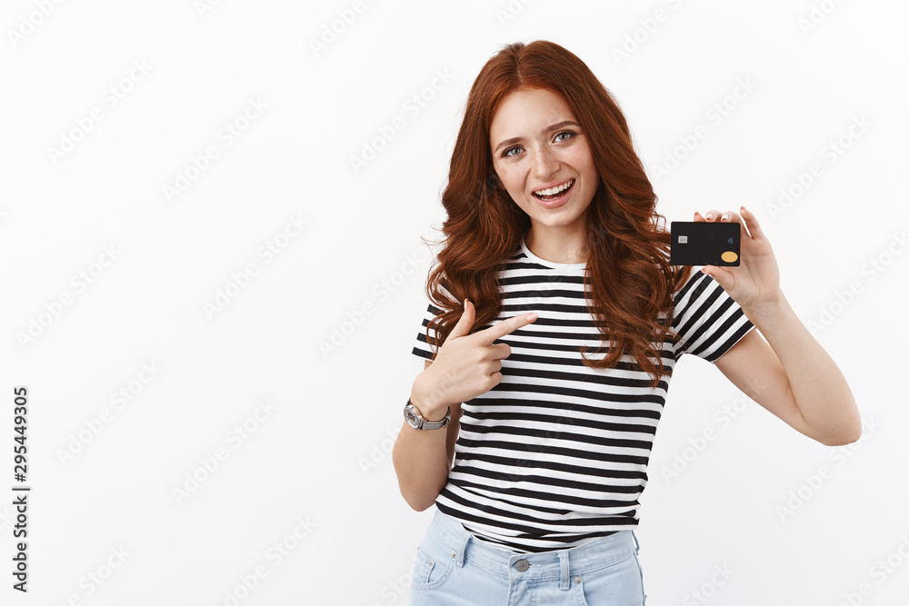 Best bank ever. Cheerful cute redhead girl opened deposit gather money for summer holiday, pointing at black credit card and smiling joyfully, paying online, using cashback to pay for coffee Best bank ever. Cheerful cute redhead girl opened deposit gather money for summer holiday, pointing at black credit card and smiling joyfully, paying online, using cashback to pay for coffee