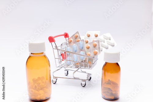 shopping cart with pills, medicines and bottles of medicines on white background. pharmacy medicines.