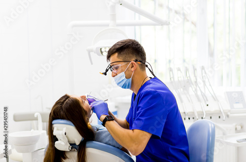 Dentist curing a female patient s caries in tooth. Dentis examines the teeth in dental clinic office.