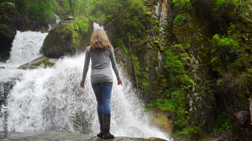 a young girl stands at the waterfall a young girl stands at the waterfall