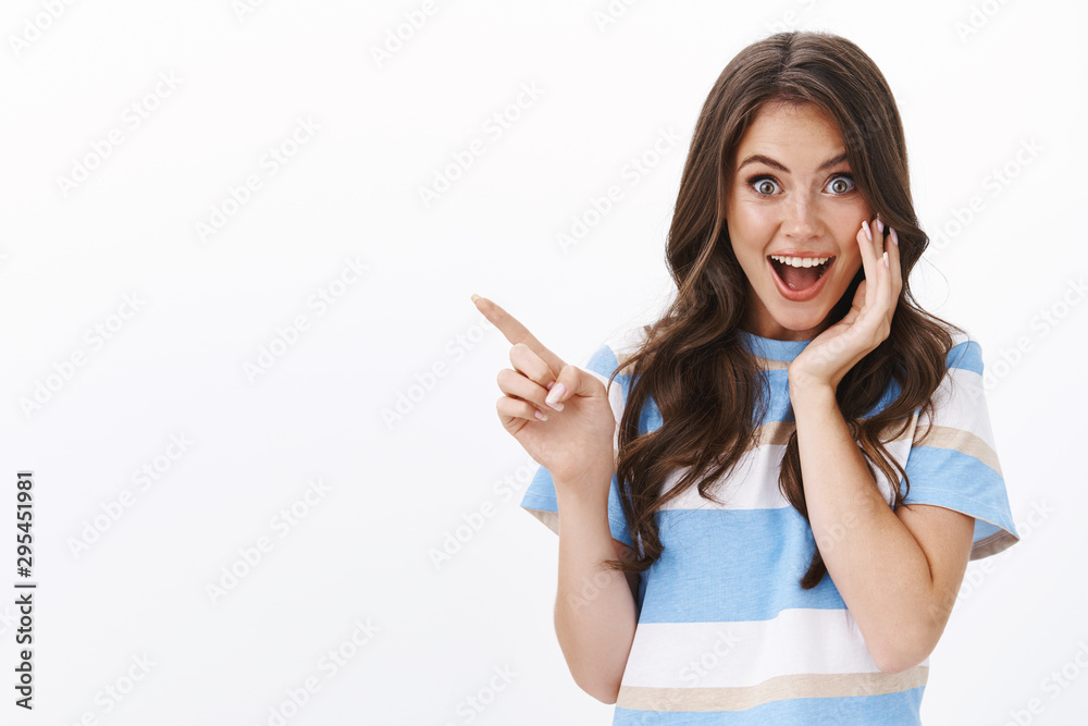 Foto de Enthusiastic joyful surprised woman introduce incredible offer, pointing finger left Foto de Enthusiastic joyful surprised woman introduce incredible offer, pointing finger left