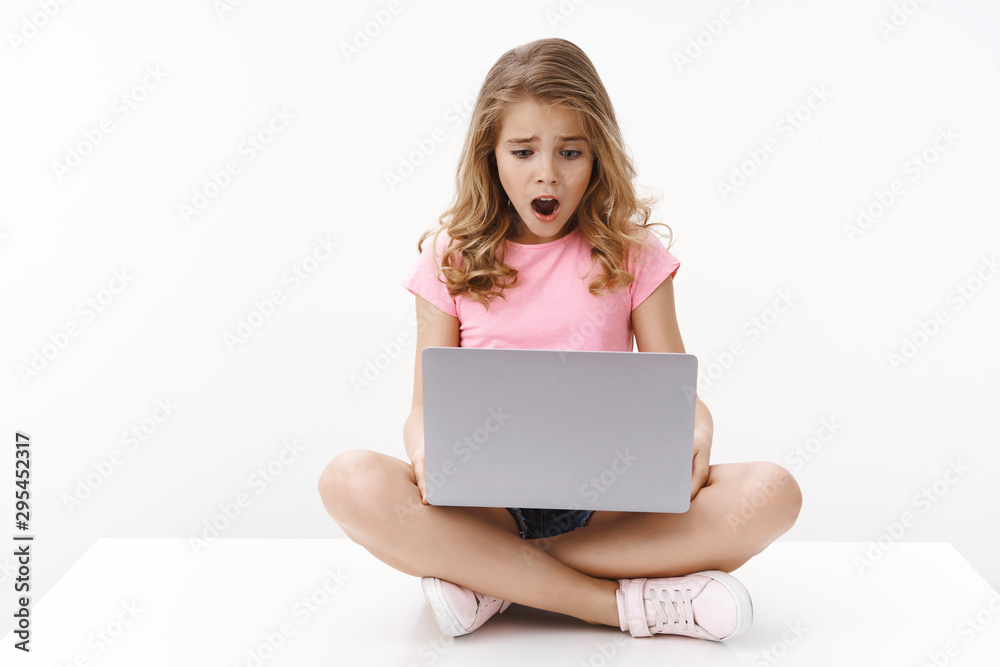 Upset cute blond little kid getting sad and disappointed checking school account, receive terrible mark, sit crossed legs laptop, open mouth gasping look computer screen shocked, white background Upset cute blond little kid getting sad and disappointed checking school account, receive terrible mark, sit crossed legs laptop, open mouth gasping look computer screen shocked, white background