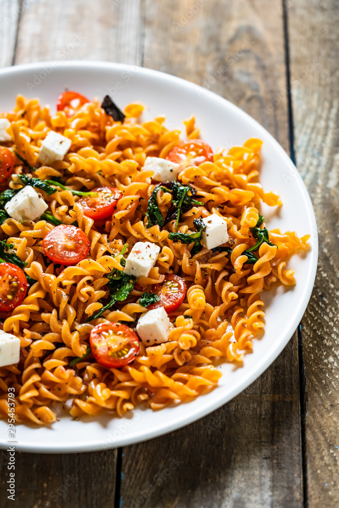 Pasta with tomatoes and white cheese on wooden table Pasta with tomatoes and white cheese on wooden table