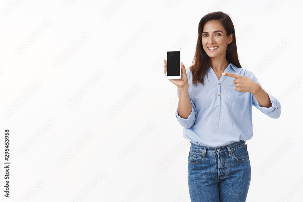 Elegant pleased good-looking cheerful adult lady promote smartphone, hold mobile phone, pointing gadget screen recommend use app, show summer vacation pics display, smiling happily Elegant pleased good-looking cheerful adult lady promote smartphone, hold mobile phone, pointing gadget screen recommend use app, show summer vacation pics display, smiling happily