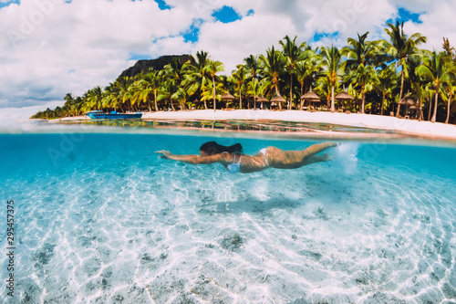 Young attractive woman swimming underwater in transparent blue ocean at Mauritius