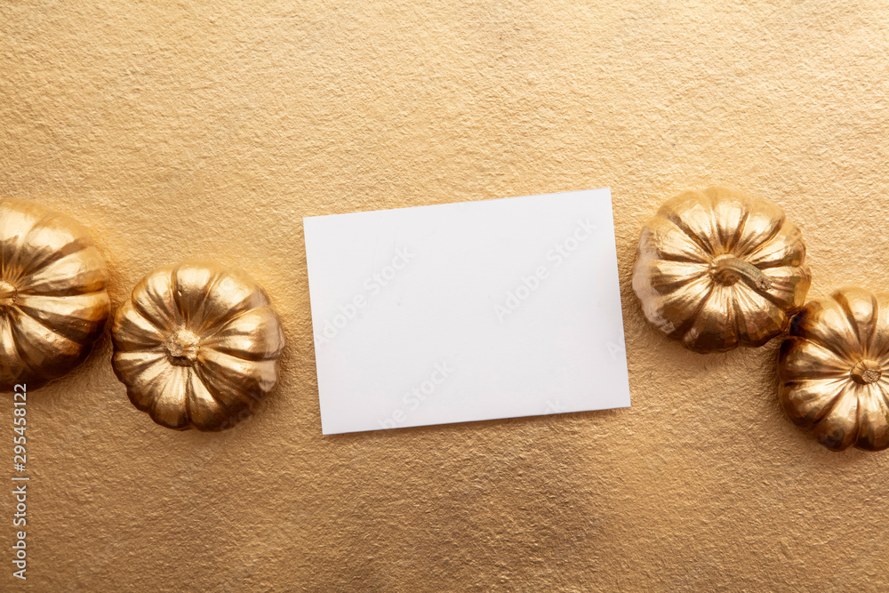 Golden thanksgiving pumpkin and blank card overhead flay lay composition Golden thanksgiving pumpkin and blank card overhead flay lay composition