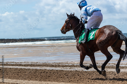 Race horse and jockey galloping on a sandy beach © Gabriel Cassan