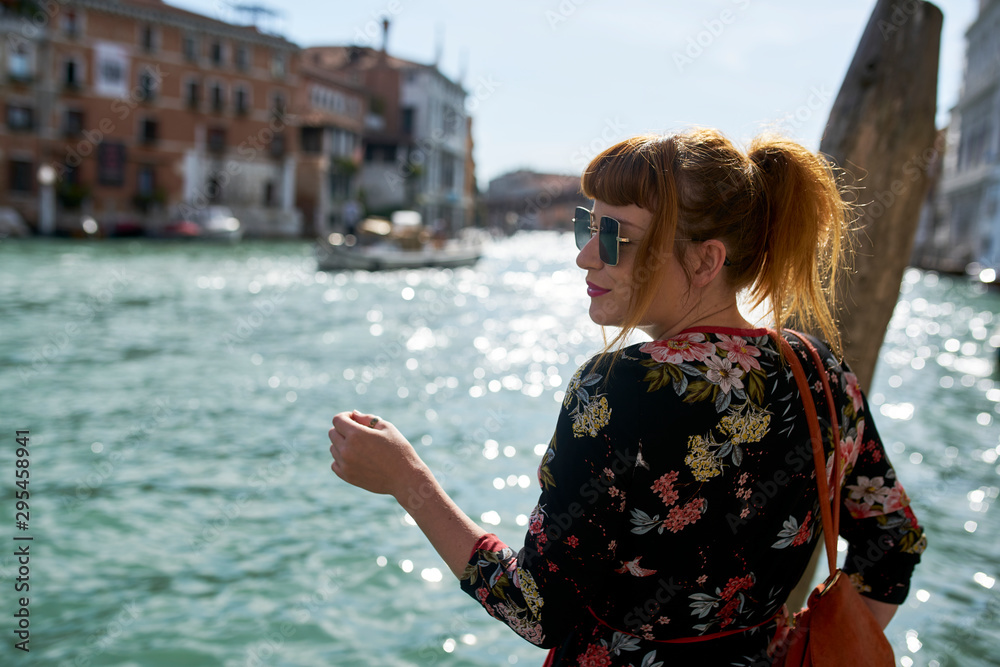 Caucasian redhead woman with floral dress looking at grand canal Venice