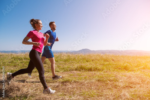 young couple jogging on sunny day at summer mountain