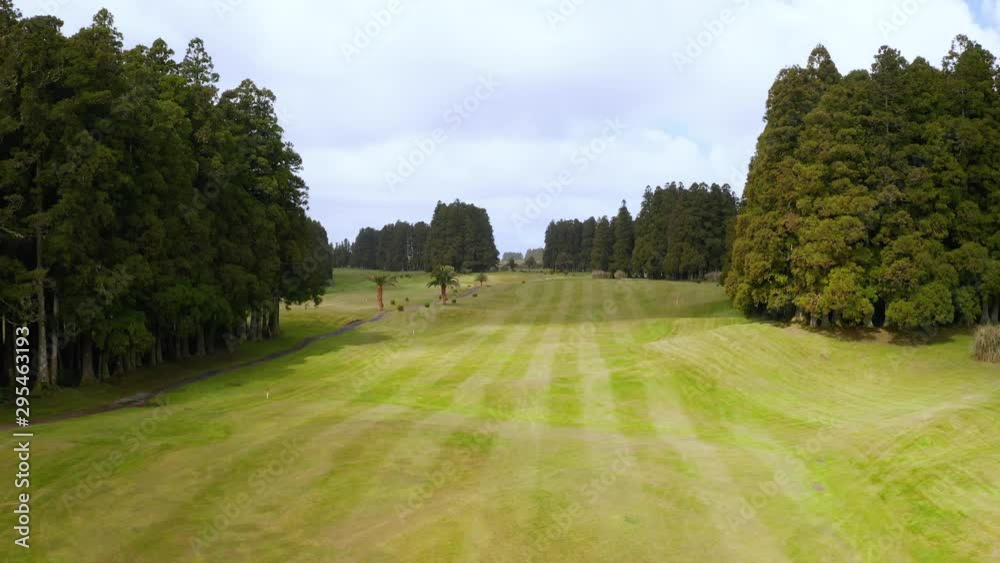 Flying above golf course, green trees and palms. Sunlight and cloud shadows on green grass. Aerial of San Miguel, Azores Flying above golf course, green trees and palms. Sunlight and cloud shadows on green grass. Aerial of San Miguel, Azores