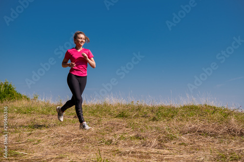 young woman jogging on sunny day at summer mountain