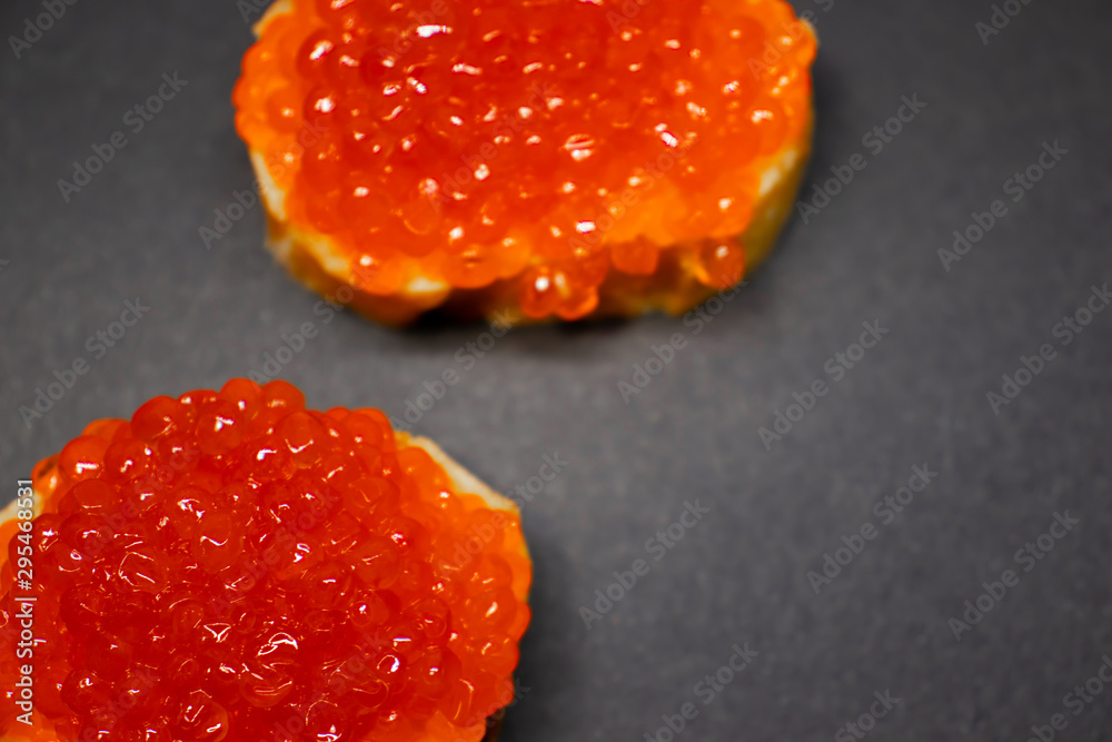 Two red salmon caviar canape close up on white baguette. Two red salmon caviar canape close up on white baguette.
