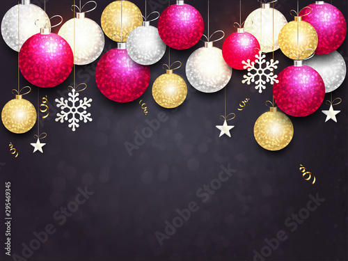 Colorful baubles and snowflakes hang on black background for festival celebration concept.
