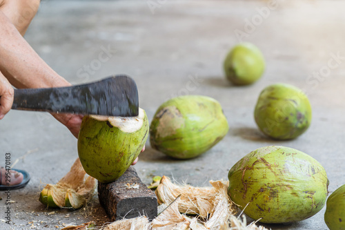 Green fresh coconut peeling and shelling with heavy chop knife for juice.