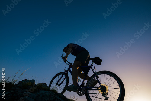 Fototapeta Naklejka Na Ścianę i Meble -  Silhouette of a mountain biker riding his mountain sportbike on top of a cliff ( hill).