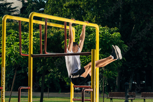 Handsome man doing pull-ups during outdoors crossfit training