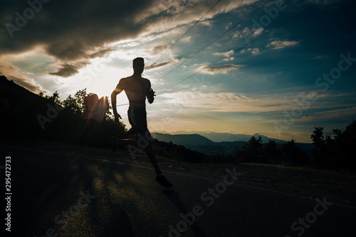 Silhouette of a man running with resistance parachute at sunrise with the sun in the background