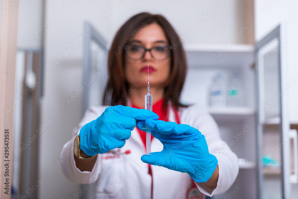 Close up od a female doctor ( nurse ) holding a syringe while standing in a medical office Close up od a female doctor ( nurse ) holding a syringe while standing in a medical office