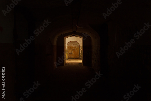 Lighted door at the exit of a dark underground tunnel in fort Pospelova, Vladivostok.