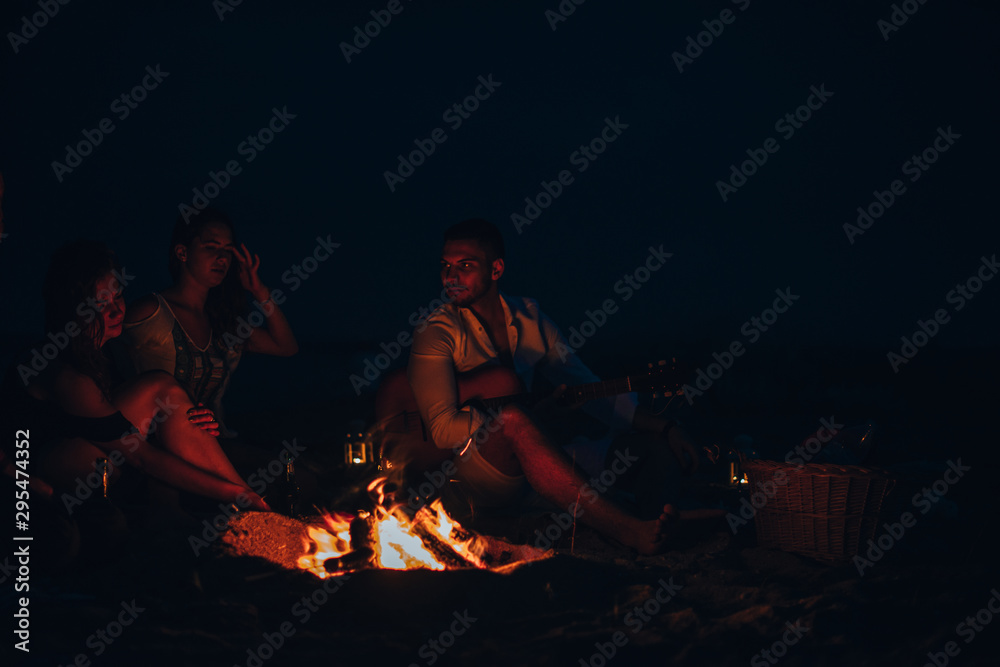 Fototapeta premium Friends roasting sausage at the beach in the night