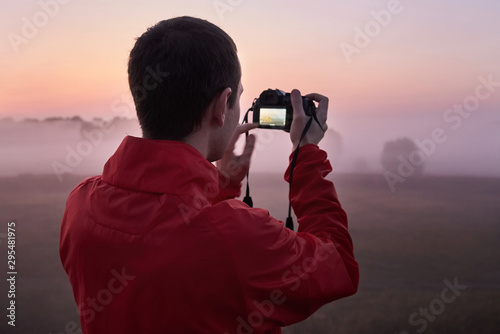 A man photographs a dense fog on an early morning at dawn.