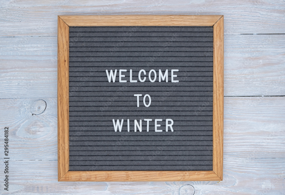 grey felt Board with English text welcome to winter. top view on wooden background