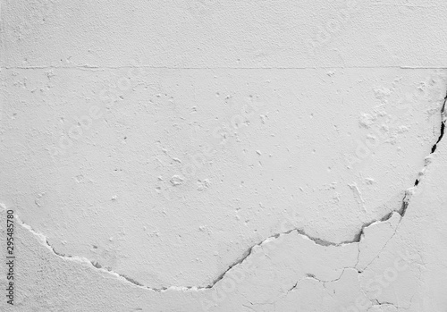Close-up of a cracked concrete wall painted in white. High resolution full frame textured background in black and white.