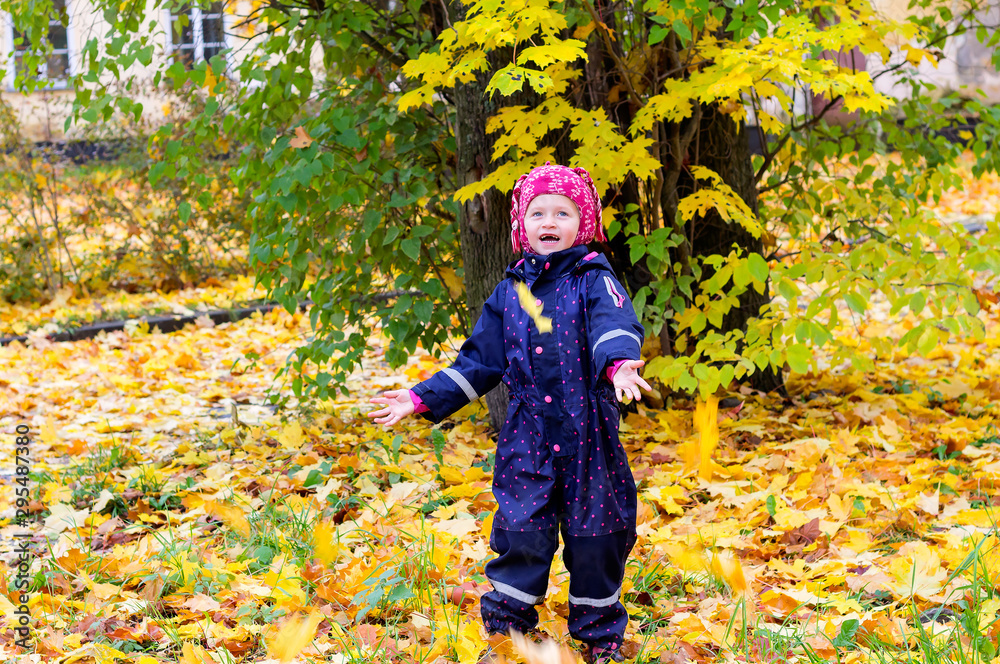 Little girl walks in the park and catches falling leaves from a tree Little girl walks in the park and catches falling leaves from a tree
