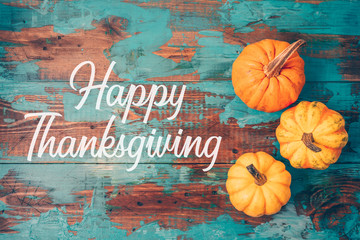 Happy Thanksgiving greeting card with pumpkin over wooden background.