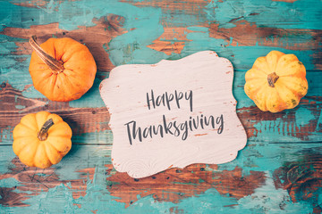 Happy Thanksgiving greeting card with pumpkin over wooden background.