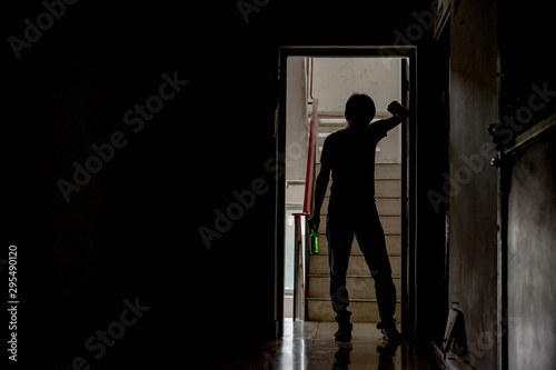 Silhouette of drunken man hold beer bottle walked into the old apartment are having stress in life and unable to find a solution and no advisor, from work problems And a failed family life. © thebigland45