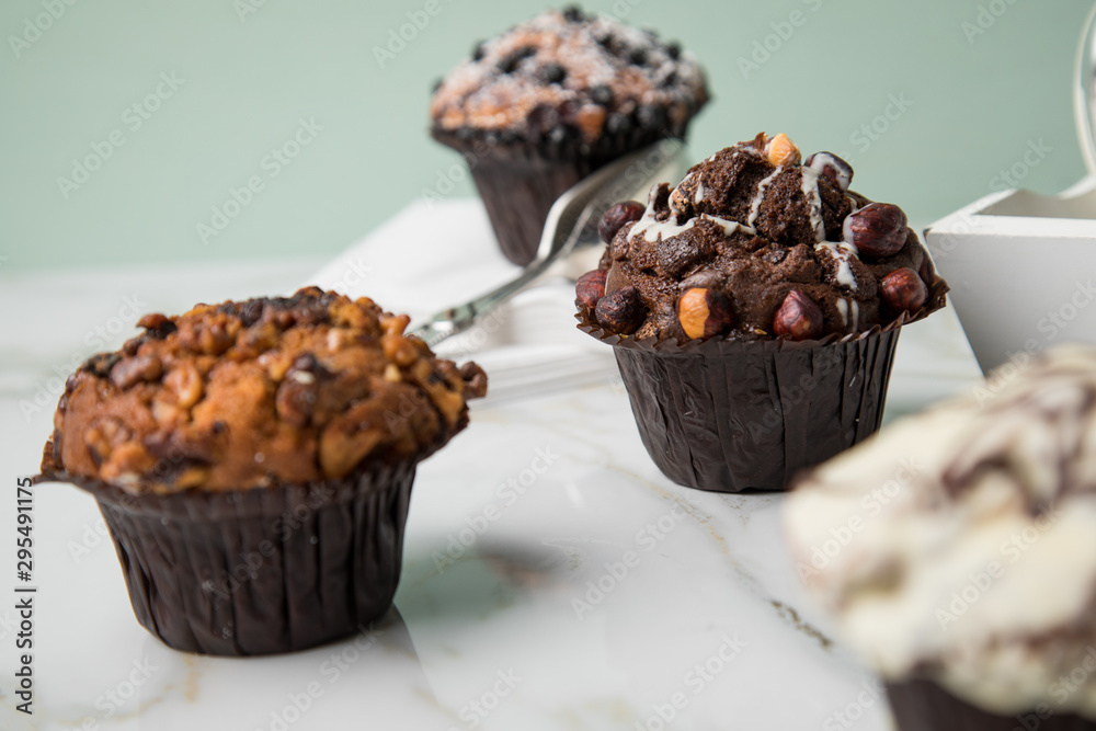 Muffin Auswahl mit Blaubeeren, Walnuss, Haselnuss und Weiße Schokolade mit Milch und Zucker für Kaffeepause auf Marmor Tisch und Grün Hintergrund Muffin Auswahl mit Blaubeeren, Walnuss, Haselnuss und Weiße Schokolade mit Milch und Zucker für Kaffeepause auf Marmor Tisch und Grün Hintergrund