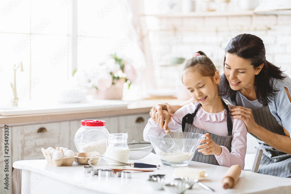 Happy mother and daughter making dough in kitchen together Happy mother and daughter making dough in kitchen together