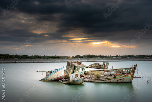 The Noirmoutier boats cemetery. A group of wrecks of old wooden fishing boats are piled up and do not float at high tide photo