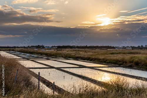 Salt marshes on the island of Noirmoutier in France..The sun rises on ponds, basins and .salt piles