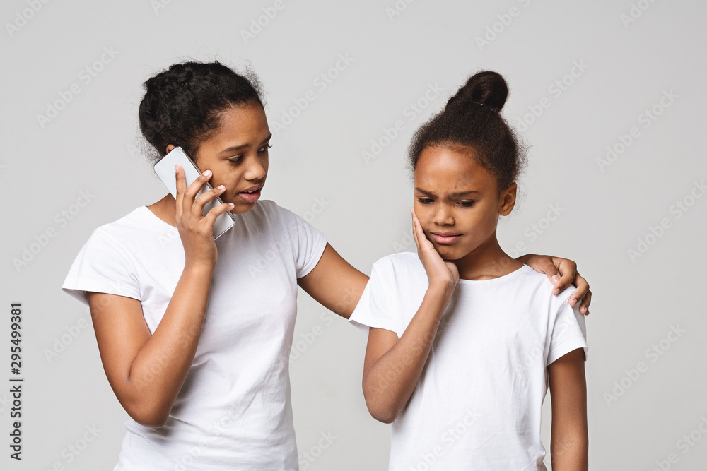Little black girl suffering from tooth pain on grey background Little black girl suffering from tooth pain on grey background