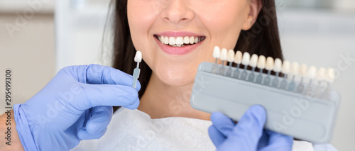 Dentist applying sample from tooth scale to happy patient teeth