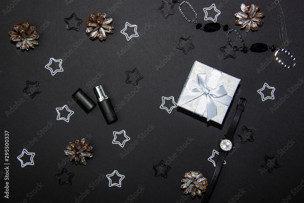 Obraz premium Beautiful Christmas composition on a black background with a Christmas gift box, cosmetics and Christmas decorations. View from above. Copy space