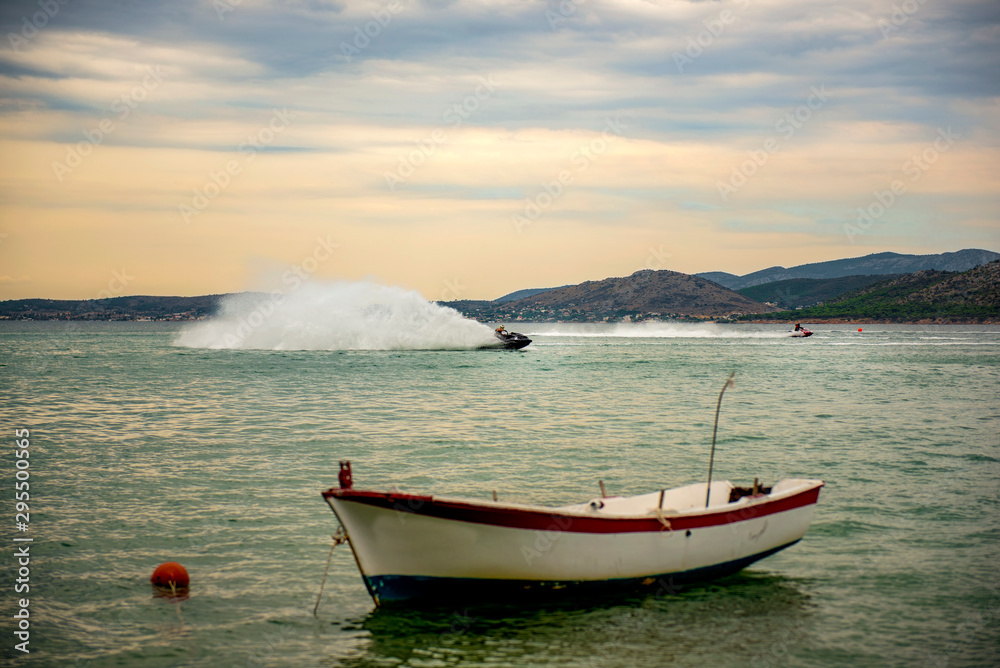 Jetski against traditional wooden fishing boats at sunset