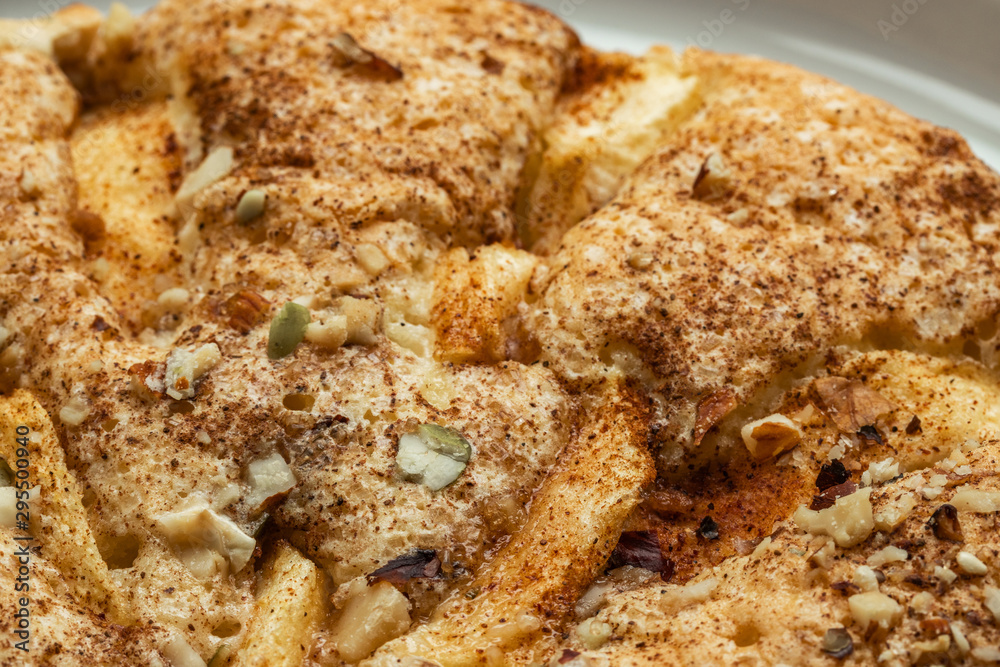 Sponge cake with apples, crushed walnuts and cinnamon lies on a white plate, close-up, side view from above Sponge cake with apples, crushed walnuts and cinnamon lies on a white plate, close-up, side view from above