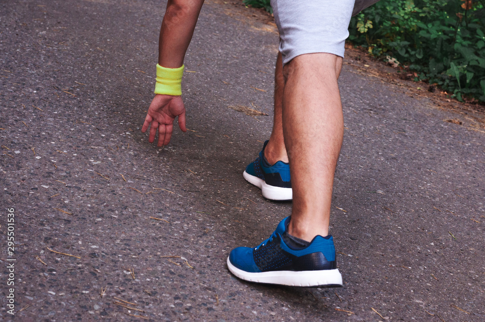 Feet step runner on the road, closeup shoes. Start running on the sidelines. Run outdoor exercise activity concept. Young handsome man jogging along a scenic path in a park. Feet step runner on the road, closeup shoes. Start running on the sidelines. Run outdoor exercise activity concept. Young handsome man jogging along a scenic path in a park.