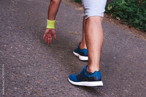 Feet step runner on the road, closeup shoes. Start running on the sidelines. Run outdoor exercise activity concept. Young handsome man jogging along a scenic path in a park.