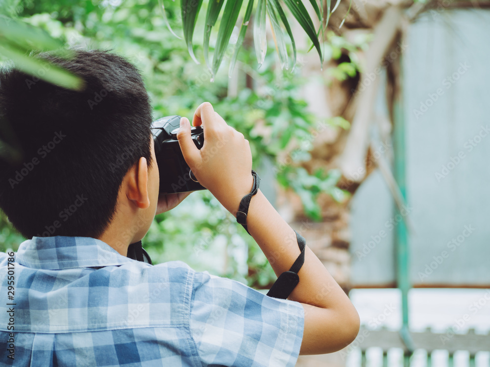 Young asian boy looking for attractive and taking photo by camera on forest background and nature holiday. Travel concept Young asian boy looking for attractive and taking photo by camera on forest background and nature holiday. Travel concept