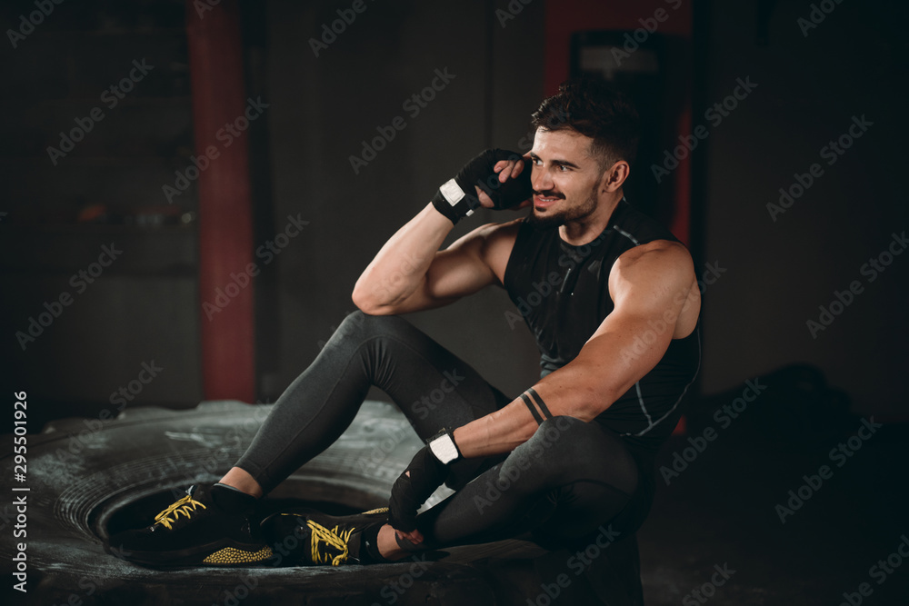 In the gym class good looking athletic guy speaking on his phone after a hard workout exercises he have a happy and smiling face
