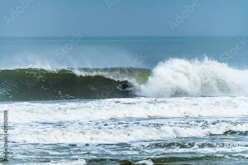 Bodyboarder surfing ocean wave on a sunny day. © homydesign