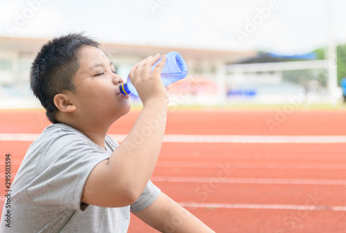 Fat asian boy drink water from a plastic bottle